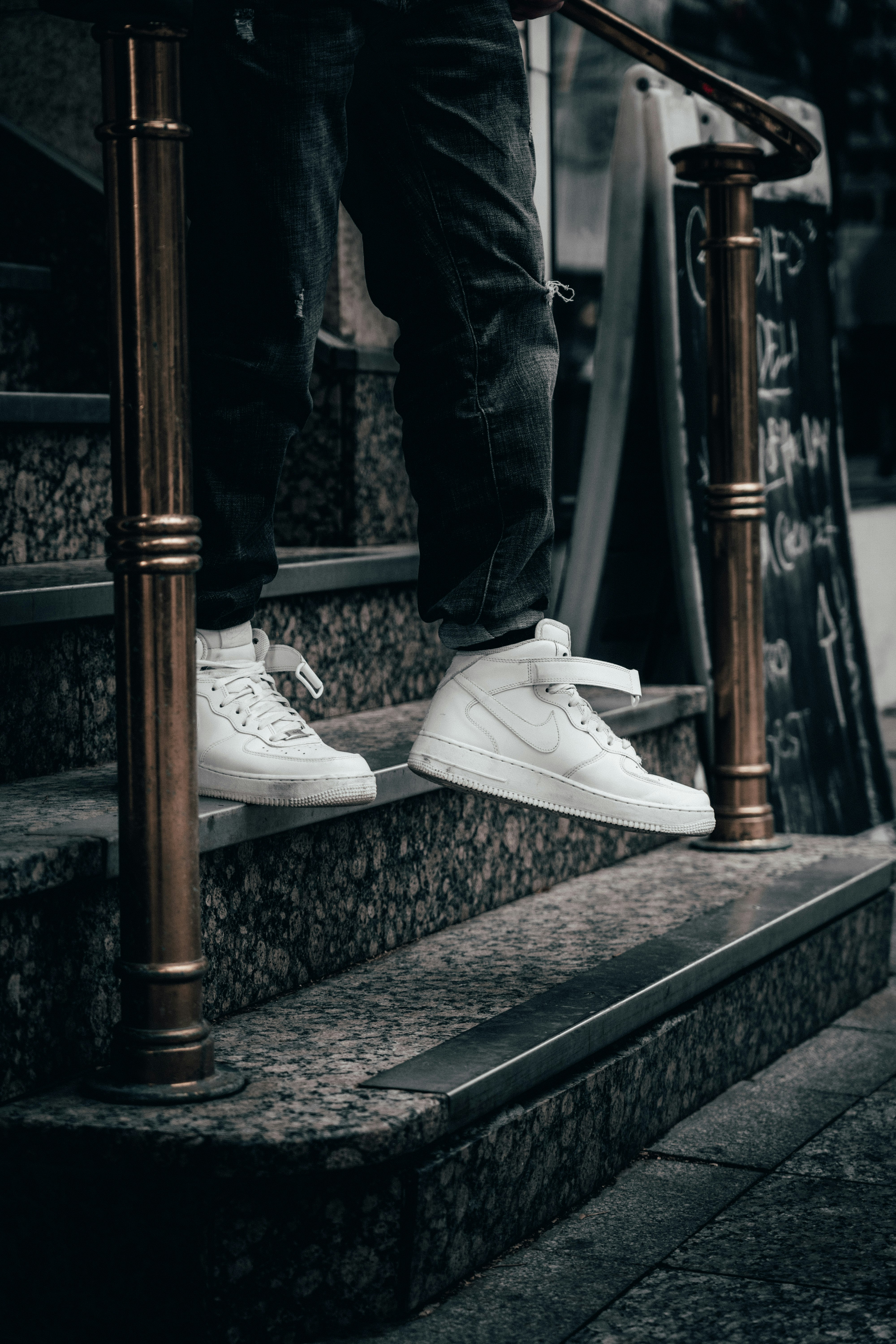 person in black denim jeans and white nike sneakers